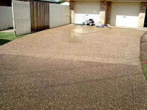 Half-washed exposed-aggregate driveway showing the contrast between cleaned and uncleaned concrete